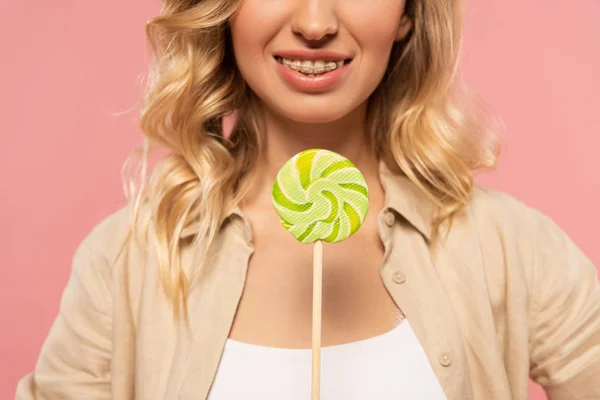 Cropped view of woman with dental braces holding lollipop isolated on pink — Stock Photo