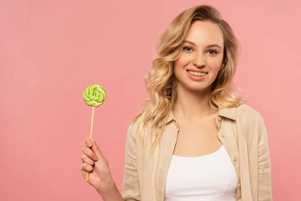 Mulher sorridente com aparelho dentário segurando pirulito isolado em rosa — Fotografia de Stock