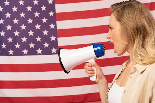 Junge Frau schreit in Lautsprecher mit amerikanischer Flagge im Hintergrund — Stockfoto