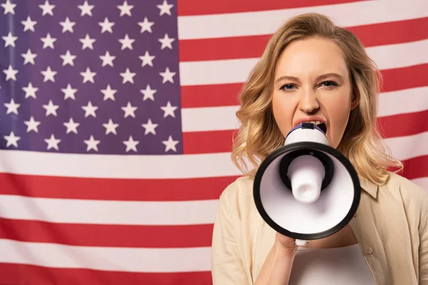 Jovem mulher gritando em alto-falante com bandeira americana no fundo — Fotografia de Stock