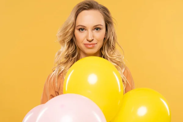Улыбающаяся блондинка держит воздушные шары изолированные на желтый — стоковое фото
