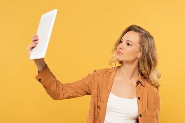 Mulher loira a tomar selfie com comprimido digital isolado em amarelo — Fotografia de Stock