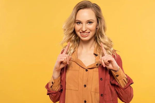 Lächelnde Frau zeigt mit gelb isolierten Fingern nach oben — Stockfoto