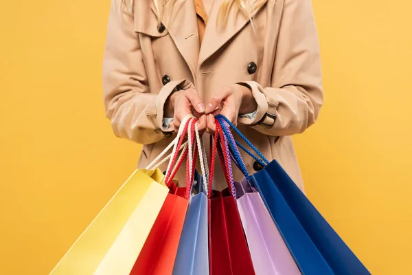 Vista cortada da mulher segurando sacos de compras isolados no amarelo — Fotografia de Stock