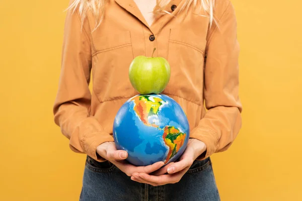 Vista recortada de la mujer sosteniendo globo y manzana verde aislado en amarillo - foto de stock