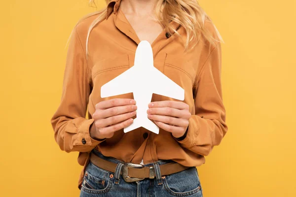 Vue recadrée d'une femme tenant un avion en papier isolé sur jaune — Photo de stock