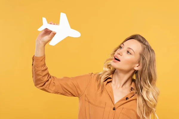 Femme blonde jouant avec un avion en papier isolé sur jaune — Photo de stock