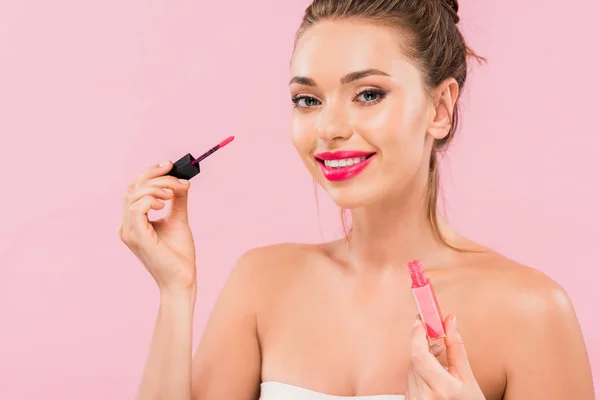 Lächelnd nackt schöne Frau mit rosa Lippen hält Lipgloss isoliert auf rosa — Stockfoto