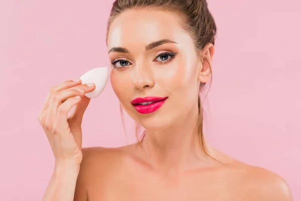 Naked beautiful woman with pink lips holding makeup sponge isolated on pink — Stock Photo