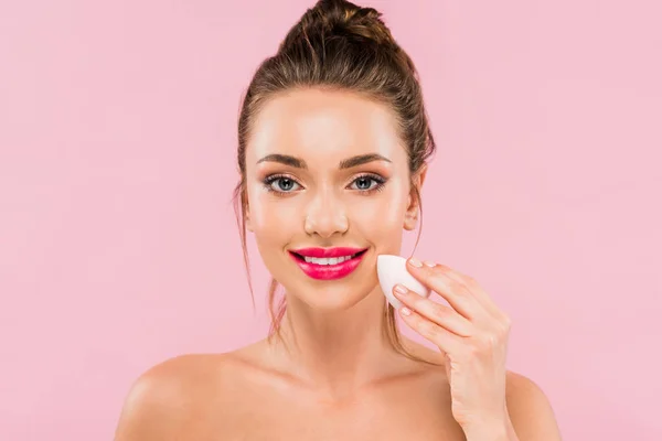 Smiling naked beautiful woman with pink lips holding makeup sponge isolated on pink — Stock Photo