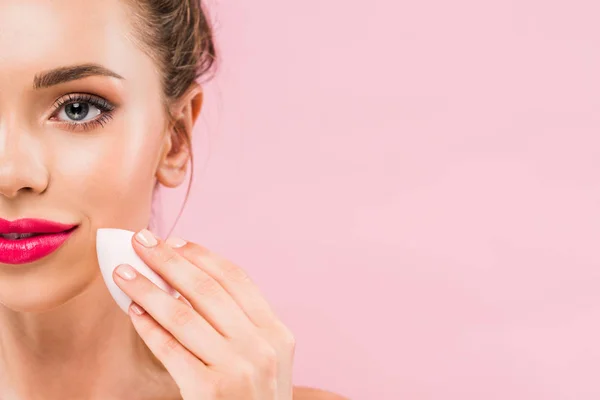 Vista recortada de mujer hermosa desnuda con labios rosados que sostienen esponja de maquillaje aislado en rosa - foto de stock