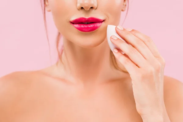 Vista recortada de mujer hermosa desnuda con labios rosados que sostienen esponja de maquillaje aislado en rosa - foto de stock