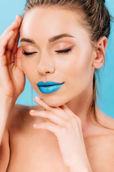 Naked beautiful woman with blue lips posing with hands near face and closed eyes isolated on blue — Stock Photo