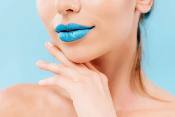 Vista recortada de hermosa mujer desnuda con labios azules posando con la mano cerca de la cara aislada en azul - foto de stock