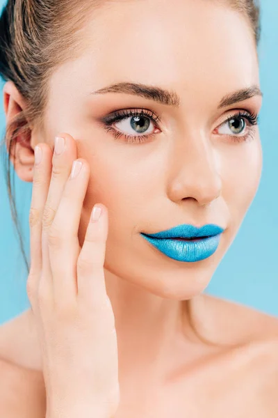 Гола красива жінка з блакитними губами торкається обличчя ізольовано на синьому — стокове фото