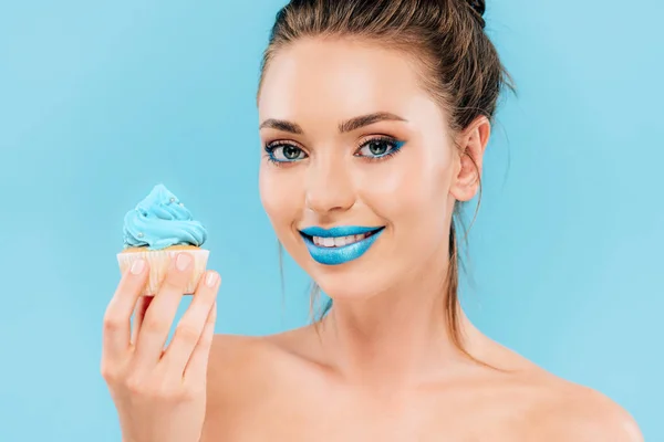 Усміхнена гола красива жінка з блакитними губами і кексом ізольована на синьому — стокове фото