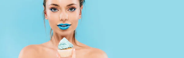 Гола красива жінка з блакитними губами і кексом ізольована на синьому, панорамний постріл — стокове фото