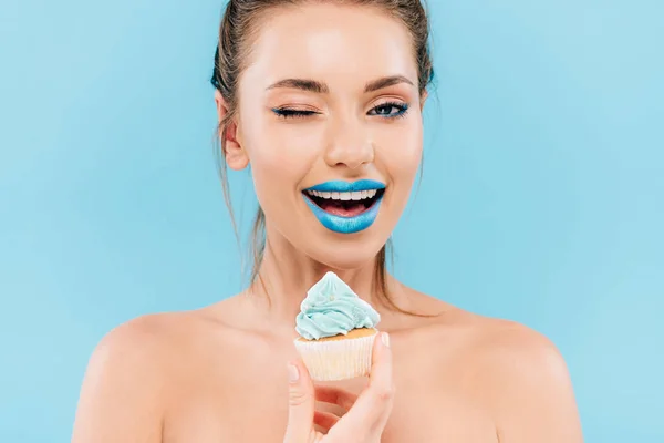 Sorrindo mulher bonita nua com lábios azuis e cupcake piscando isolado no azul — Fotografia de Stock