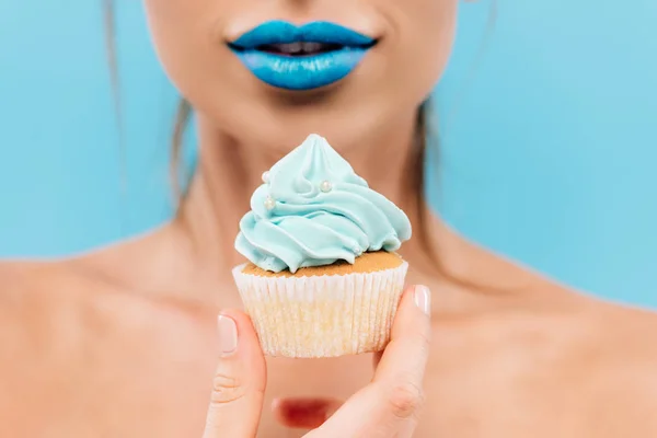 Selective focus of naked beautiful woman with blue lips and cupcake isolated on blue — Stock Photo