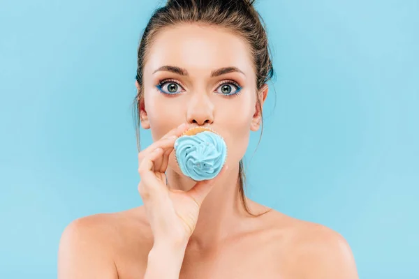 Desnudo hermosa mujer celebración cupcake en boca aislado en azul - foto de stock