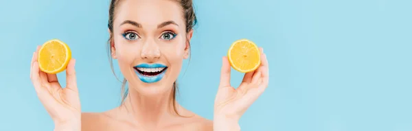 Aufgeregte nackte schöne Frau mit blauen Lippen, die orangefarbene Hälften isoliert auf blauem Grund hält, Panoramaaufnahme — Stockfoto