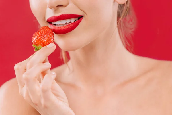 Cropped view of naked beautiful woman with red lips holding strawberry isolated on red — Stock Photo