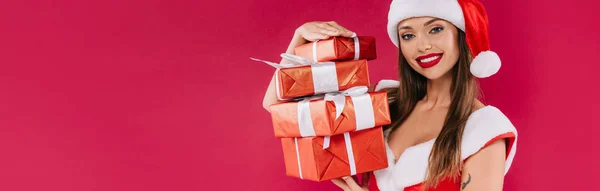 Lächelnd sexy schöne Weihnachtsmädchen mit Geschenkboxen isoliert auf Burgund, Panorama-Aufnahme — Stockfoto