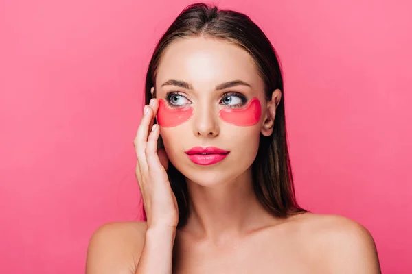 Гола красива жінка торкається плями очей на обличчі ізольована на рожевому — стокове фото