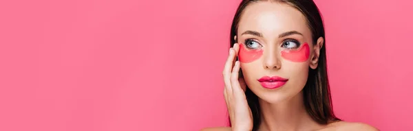Nu belle femme touchante oeil patch sur visage isolé sur rose, panoramique shot — Photo de stock