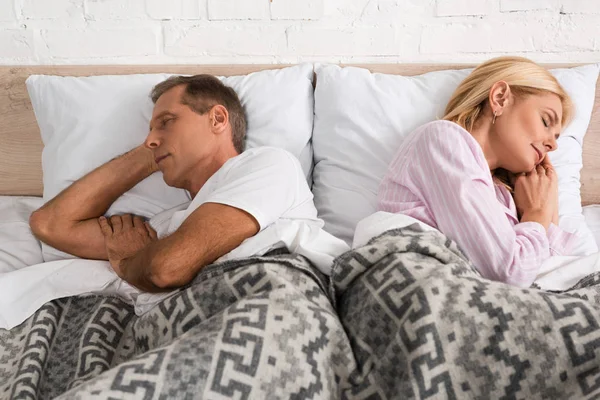 Mature couple sleeping back to back in bed — Stock Photo