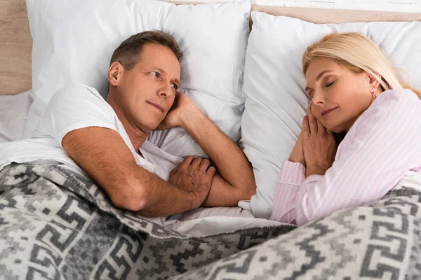 Hombre mirando a dormir esposa en la cama - foto de stock