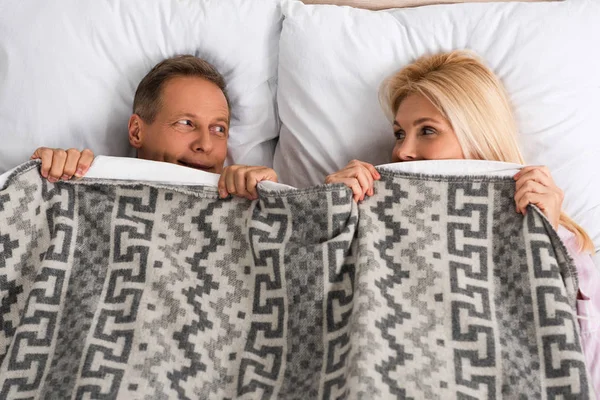 Blick von oben auf ein Paar, das sich mit einer Decke bedeckt und einander ansieht — Stockfoto