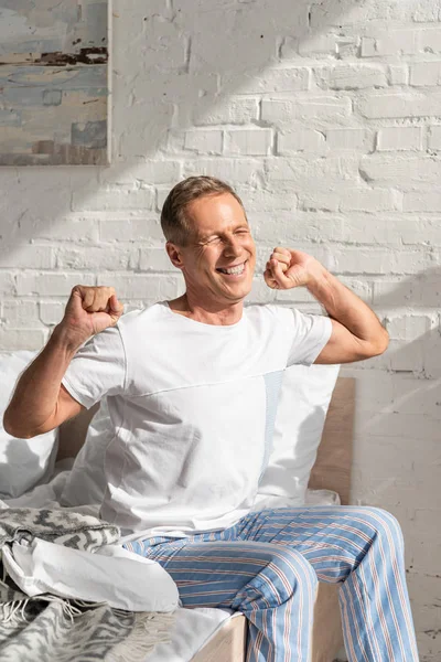 Lächelnder Mann wacht morgens auf und dehnt sich im Bett — Stockfoto