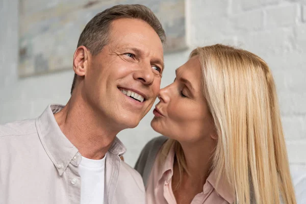 Donna baciare sulla guancia sorridente marito a casa — Foto stock
