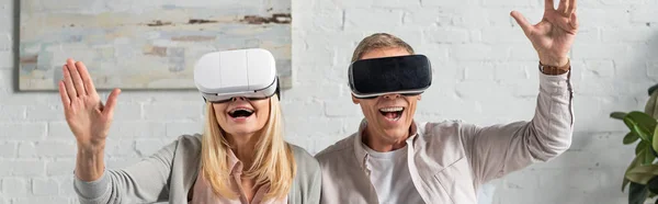 Panoramic shot of exited couple in virtual reality headsets — Stock Photo