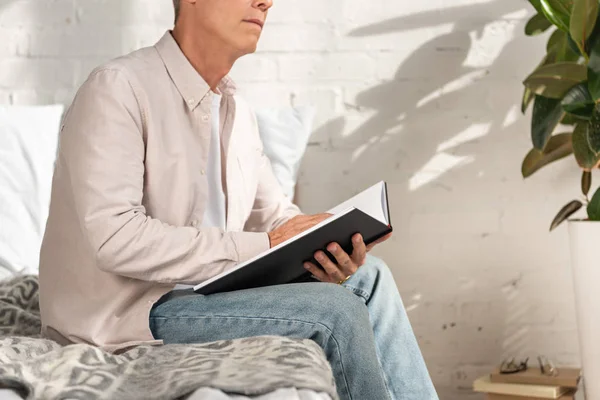 Обрезанный вид человека, держащего ноутбук на кровати — стоковое фото