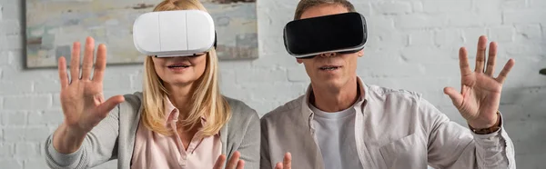 Foto panorámica de pareja usando auriculares de realidad virtual en casa - foto de stock