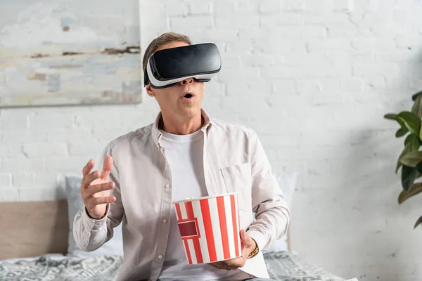 Aufgebrachter Mann in Virtual-Reality-Headset mit Popcorn auf dem Bett — Stockfoto