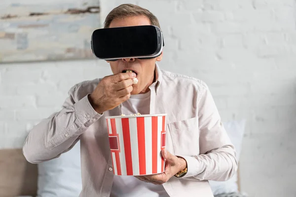Uomo in realtà virtuale auricolare mangiare popcorn sul letto — Foto stock
