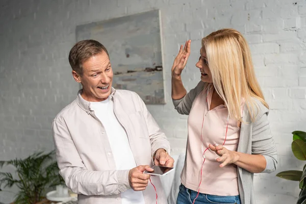 Aufgeregtes Paar hört Musik mit Kopfhörern im Wohnzimmer — Stockfoto