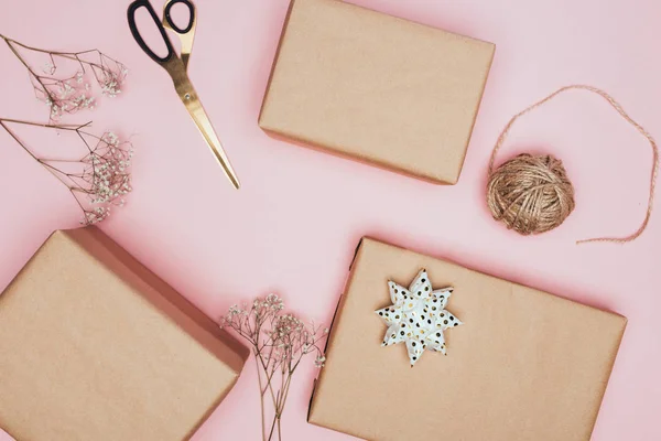 Top view of craft christmas gift boxes with scissors and flowers, isolated on pink — Stock Photo