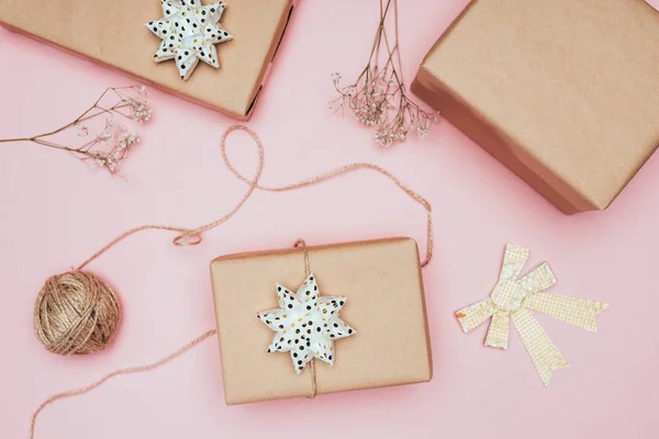 Top view of craft christmas gift boxes with flowers and bows, isolated on pink — Stock Photo