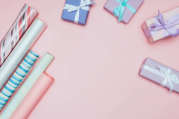 Top view of christmas gift boxes with wrapping paper rolls, isolated on pink — Stock Photo