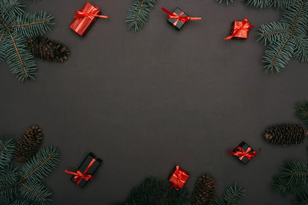 Vista superior de caixas de presente de Natal com ramos de abeto e cones de pinheiro em preto — Fotografia de Stock