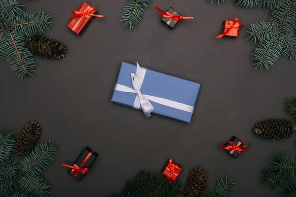 Vista dall'alto di scatole regalo di Natale con rami di abete rosso e pigne su nero — Foto stock