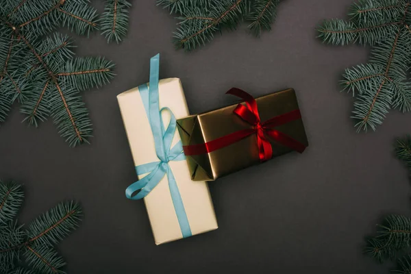 Vue du dessus des coffrets cadeaux de Noël avec des branches d'épinette sur noir — Photo de stock