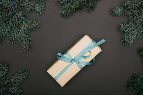 Top view of christmas gift with spruce branches on black — Stock Photo