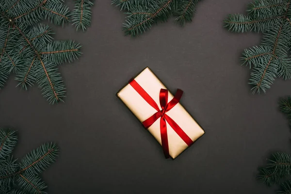 Vue du dessus du cadeau de Noël avec des branches d'épinette sur noir — Photo de stock