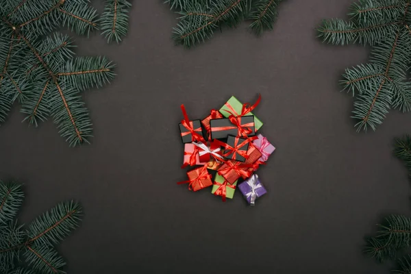 Top view of christmas gift boxes with spruce branches on black — Stock Photo