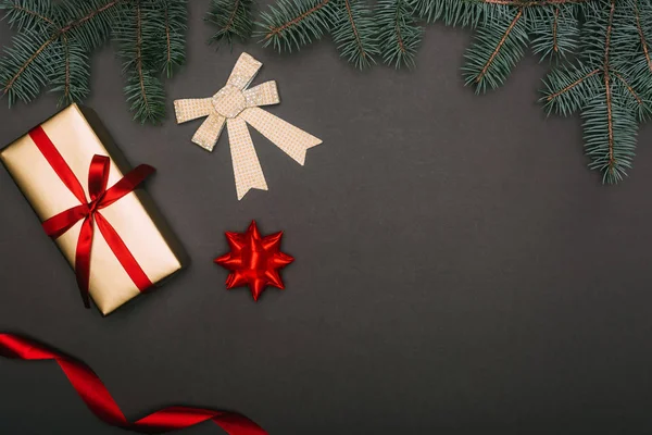 Vista superior de regalo de Navidad y arcos con ramas de abeto en negro - foto de stock